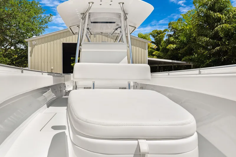 Slide: The Image of 2024 Contender 35 ST boat interior with white seating, surrounded by lush greenery and a building. - 16