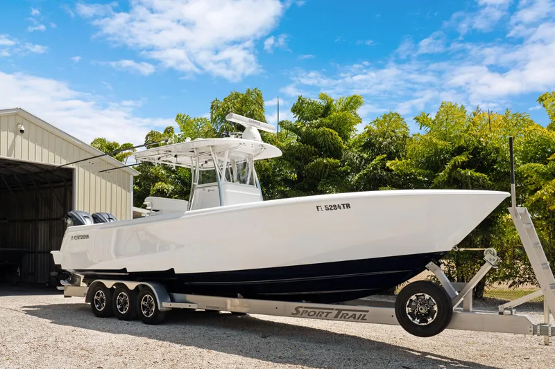 Slide: The Image of 2024 Contender 35 ST boat on trailer, parked outdoors near a shed, under a clear blue sky. - 9