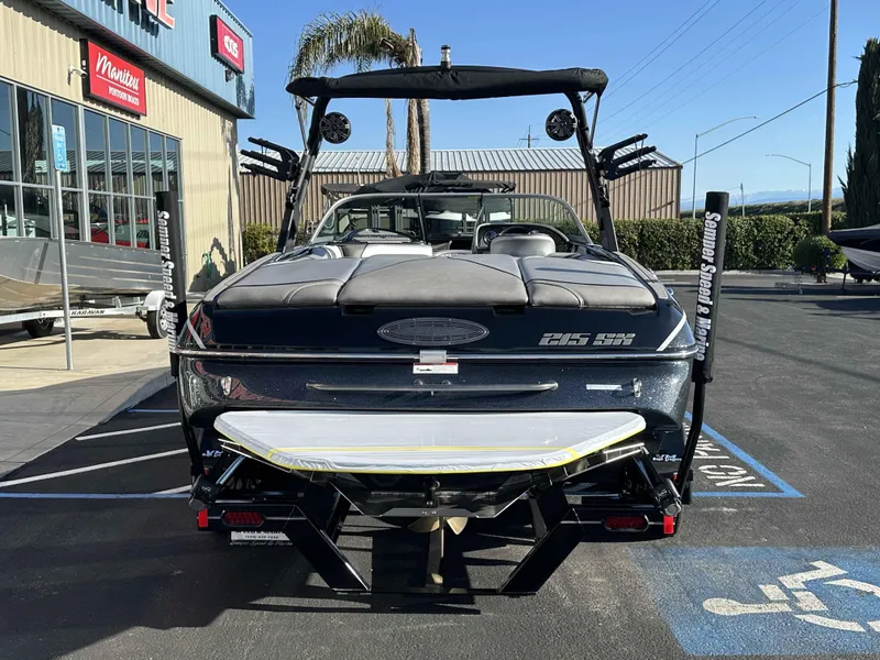 Slide: The Image of 2025 Sanger V215 SX boat parked outside a dealership on a sunny day. - 16