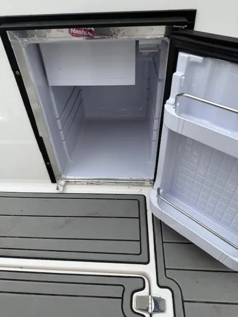 Slide: The Image of Open mini fridge on 2013 Regal 2700 Bowrider boat, showing interior and deck flooring. - 22