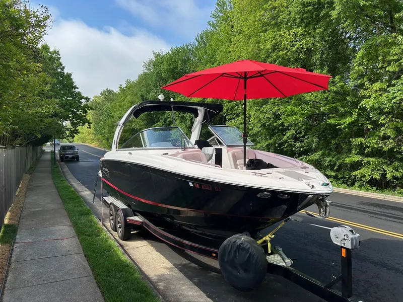 Slide: The Image of 2013 Regal 2700 Bowrider boat with red umbrella on trailer, parked roadside. - 6