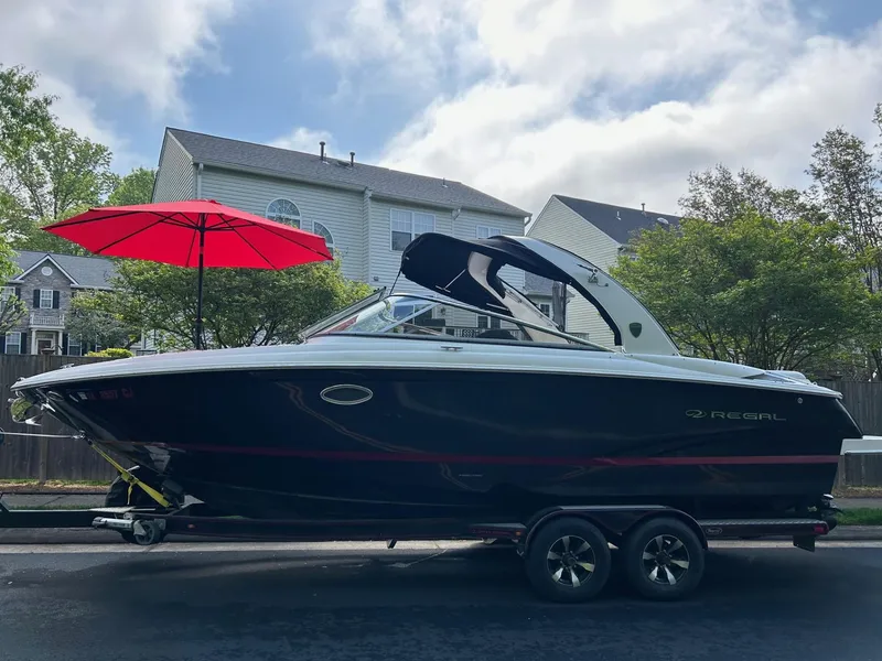 Slide: The Image of 2013 Regal 2700 Bowrider boat on trailer, parked in residential area with red umbrella. - 7