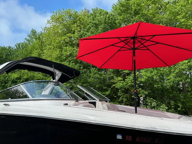 Slide: The Image of 2013 Regal 2700 Bowrider with red umbrella, set against lush green trees. - 8