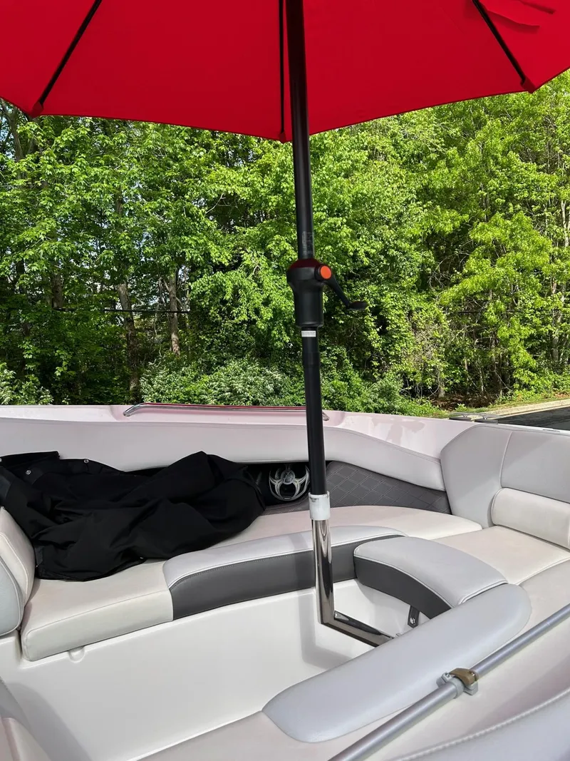 Slide: The Image of 2013 Regal 2700 Bowrider with red umbrella, white seating, and lush green background. - 9