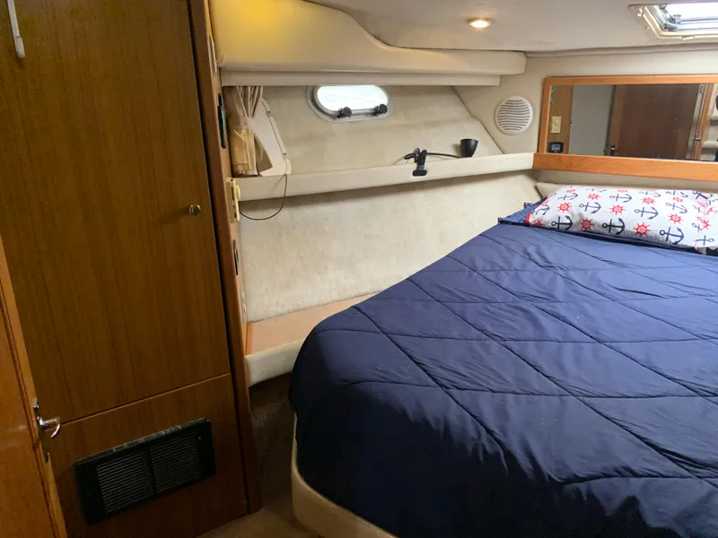 Slide: The Image of Cozy bedroom interior of 2000 Bayliner 3988 yacht with blue bedding and wooden accents. - 14