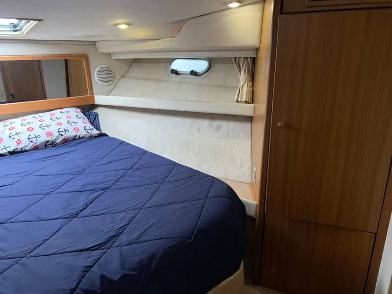 Slide: The Image of Cozy bedroom in 2000 Bayliner 3988 yacht with blue bedding and wooden cabinetry. - 15