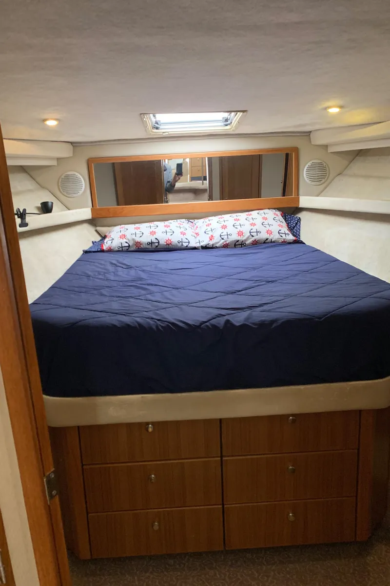 Slide: The Image of 2000 Bayliner 3988 cabin interior with bed, storage drawers, and overhead lighting. - 16