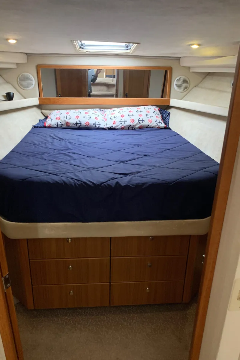 Slide: The Image of 2000 Bayliner 3988 yacht bedroom with blue bedding and wooden storage cabinets. - 17