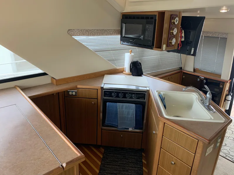 Slide: The Image of 2000 Bayliner 3988 yacht kitchen with stove, sink, and microwave in a compact layout. - 6