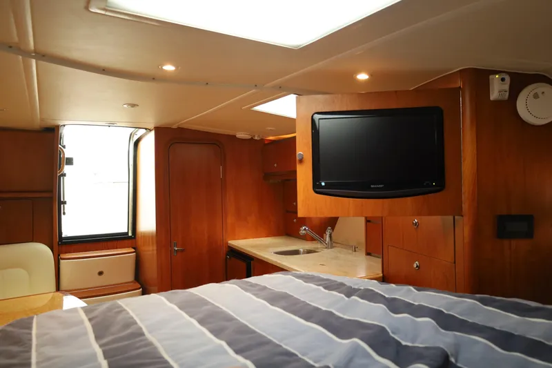 Slide: The Image of 2009 Tiara Yachts 32 Open interior with TV, kitchenette, and striped bedding. - 19
