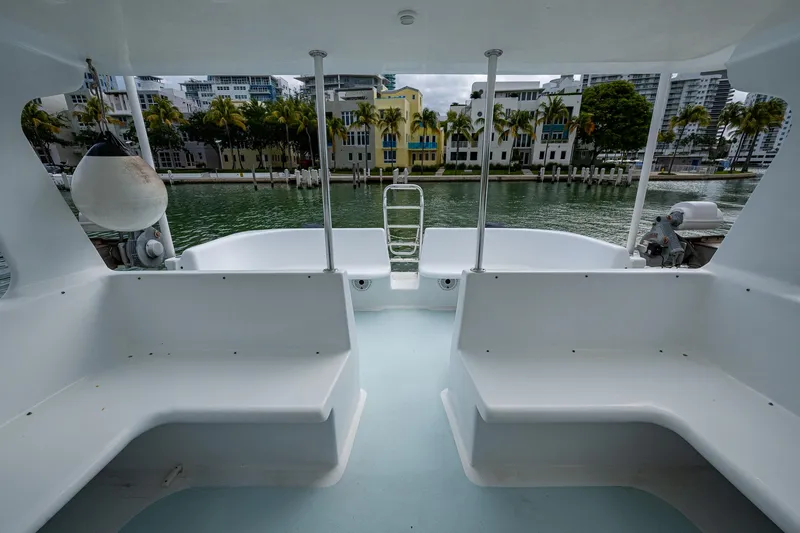 Slide: The Image of 2019 Aventura 31 Cat boat interior with waterfront view, featuring white seating and modern design. - 16