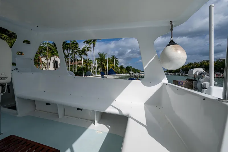 Slide: The Image of 2019 Aventura 31 Cat boat interior with white seating and scenic marina view. - 3