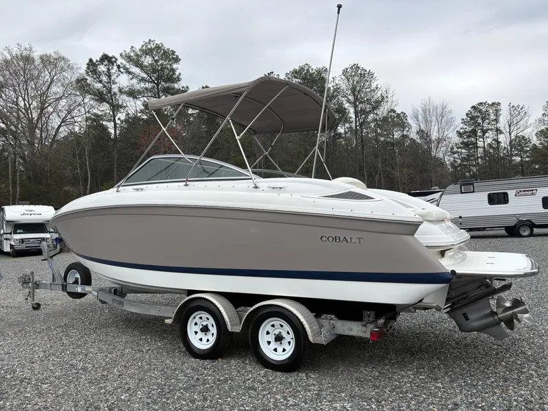 Slide: The Image of 2007 Cobalt 232 Bowrider boat on trailer, parked outdoors with trees in background. - 2