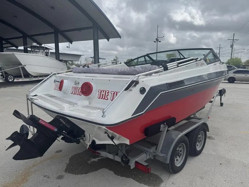 Slide: The Image of 1990 Rinker 206 Captiva Cuddy boat on trailer, red and white design, parked outdoors. - 5