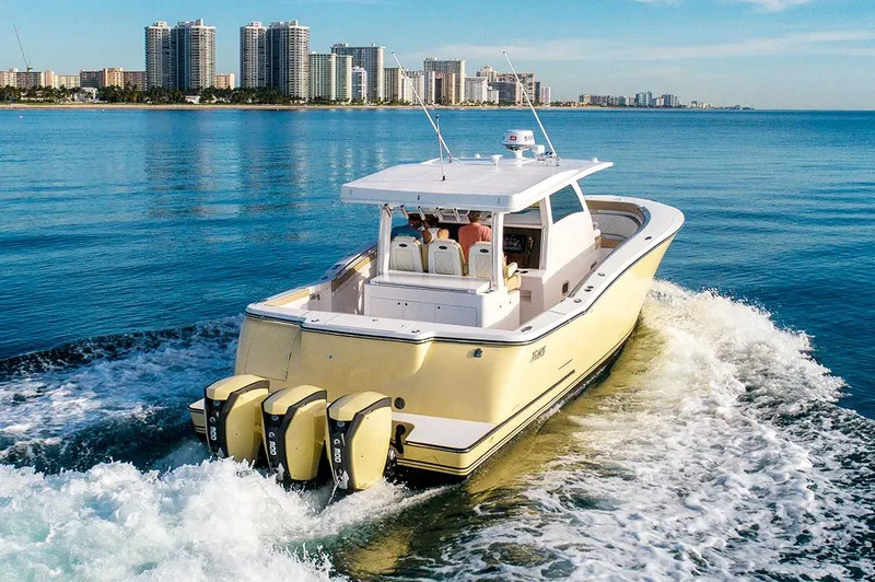 Slide: The Image of 2019 Altima 38 Xcape boat cruising on calm ocean near city skyline. - 1