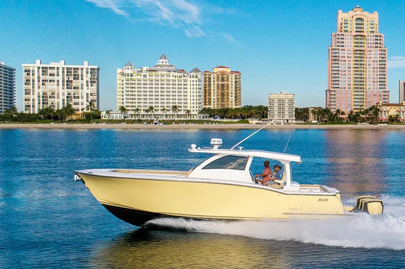 Slide: The Image of 2019 Altima 38 Xcape boat cruising on water with city skyline in background. - 2