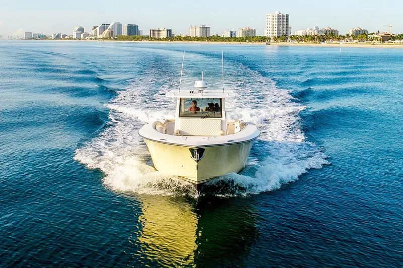 Slide: The Image of 2019 Altima 38 Xcape boat cruising on blue water near city skyline. - 4