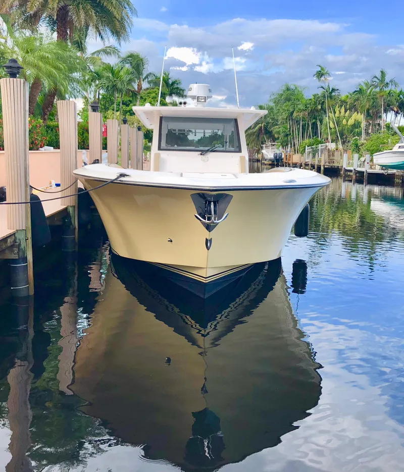 Slide: The Image of 2019 Altima 38 Xcape boat docked in a serene, tropical marina setting. - 7