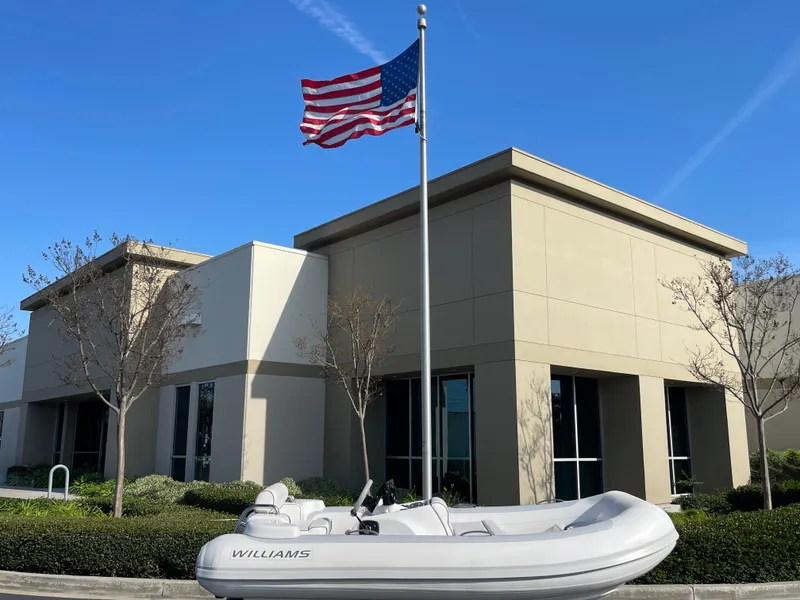 Slide: The Image of 2011 Williams Jet Tenders 325 Turbo Jet boat displayed outside modern building with American flag. - 3