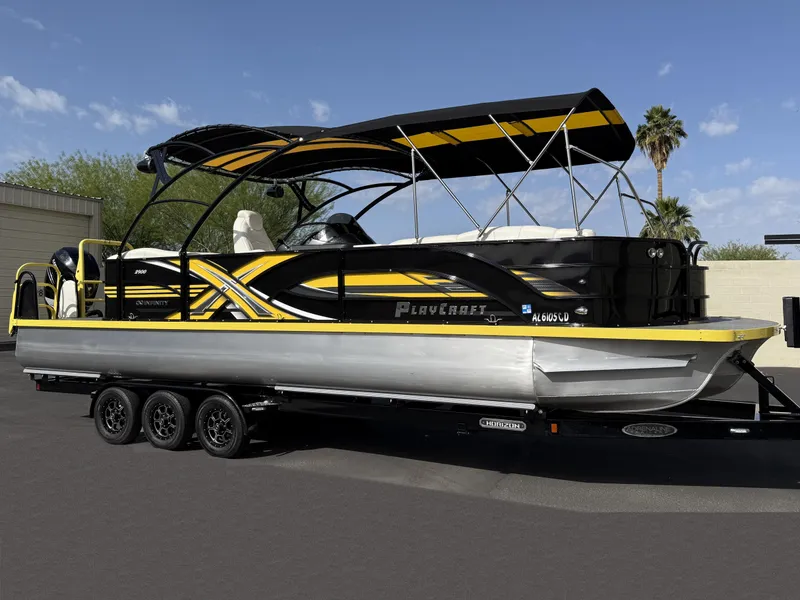 Slide: The Image of 2021 PlayCraft Infinity 2900 pontoon boat with black and yellow design on a trailer. - 1
