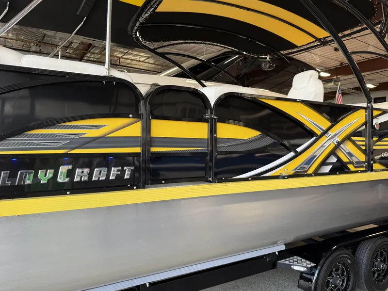 Slide: The Image of 2021 PlayCraft Infinity 2900 boat with sleek yellow and black design in a showroom. - 19
