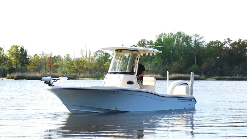Slide: The Image of 2024 Grady-White 231 Coastal Explorer boat on calm water, surrounded by trees. - 2