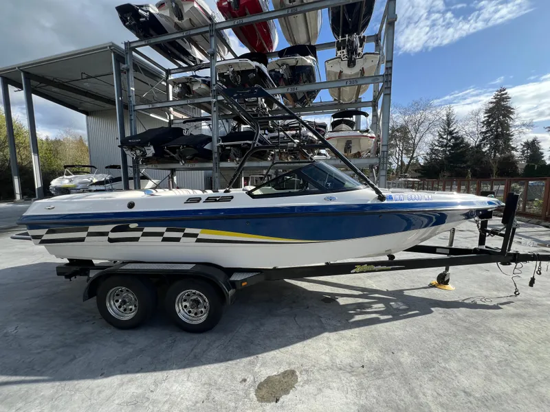 Slide: The Image of 2002 MB B52 boat on trailer, parked outdoors under a clear sky. - 5