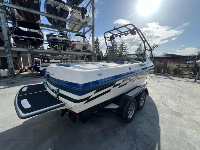 Slide: The Image of 2002 MB B52 boat on trailer under sunny sky, with storage racks in background. - 6