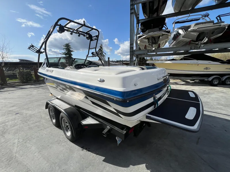 Slide: The Image of 2002 MB B52 boat on trailer under clear sky, surrounded by other boats. - 8