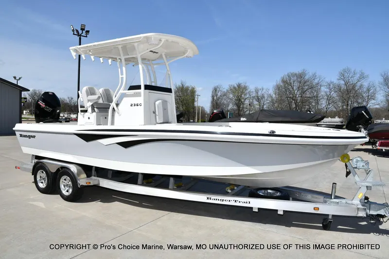Slide: The Image of 2023 Ranger 2360 Bay boat on trailer, parked outdoors under clear sky. - 1