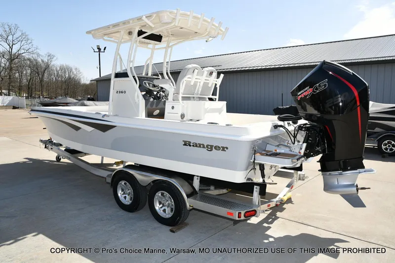 Slide: The Image of 2023 Ranger 2360 Bay boat on trailer with powerful outboard motor, parked outdoors. - 17