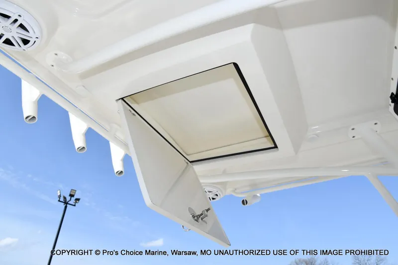 Slide: The Image of 2023 Ranger 2360 Bay boat storage compartment with rod holders and speakers, under clear blue sky. - 38