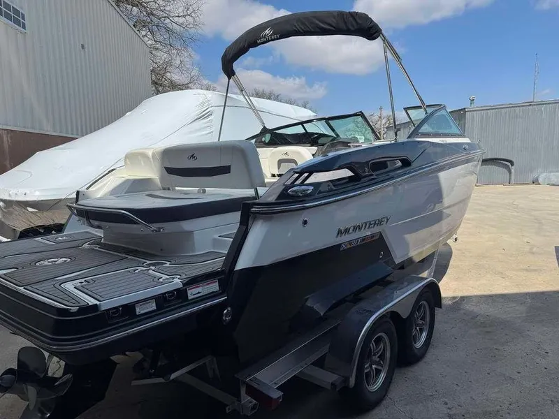 Slide: The Image of 2015 Monterey 258SS boat on trailer, parked outdoors under a clear sky. - 0