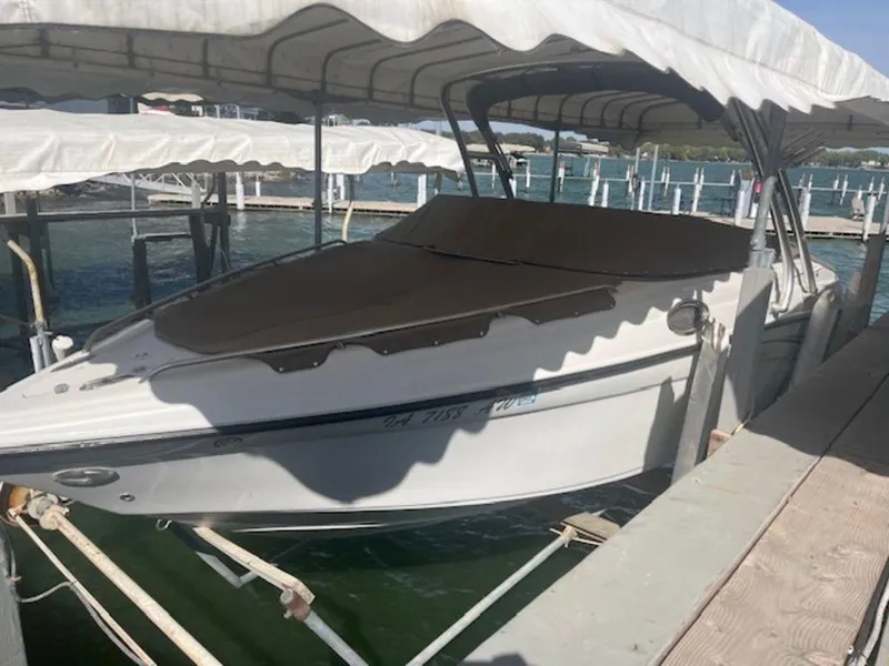 Slide: The Image of 2004 Crownline 230BR boat docked under a canopy on a sunny day. - 0