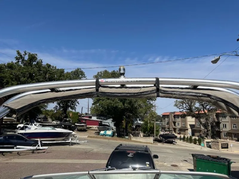 Slide: The Image of 2004 Crownline 230BR boat with a wakeboard tower, parked in a residential area. - 10