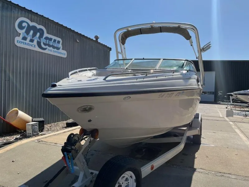 Slide: The Image of 2004 Crownline 230BR boat on trailer outside a metal building under clear sky. - 11