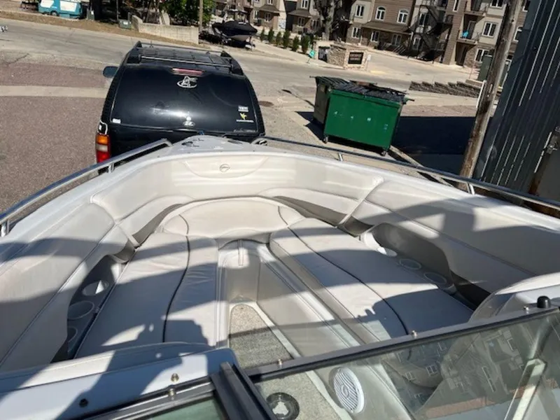 Slide: The Image of 2004 Crownline 230BR boat interior with white seating, parked near a black SUV. - 9