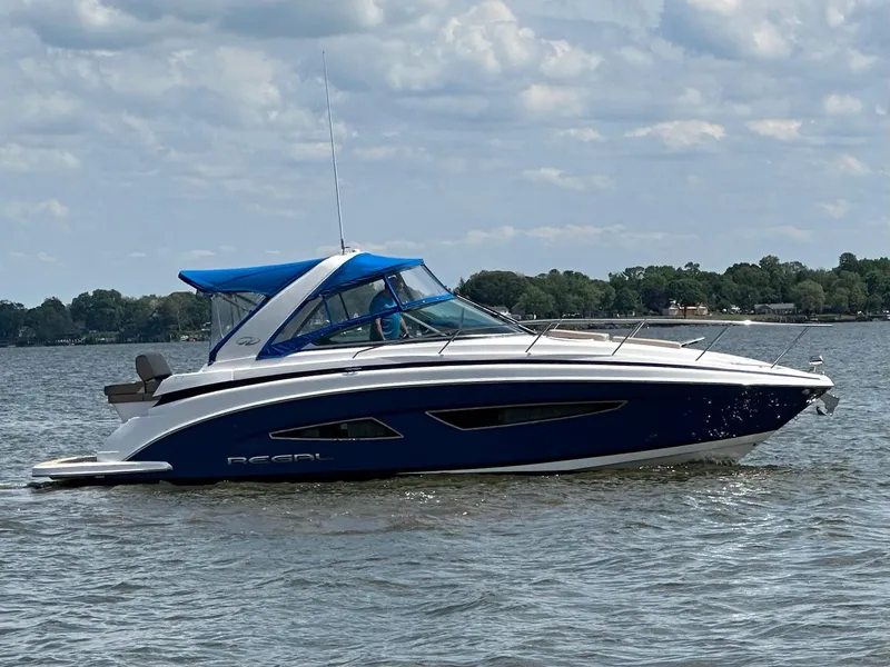 The Image of 2015 Regal 32 Express boat on a calm lake under a cloudy sky. - 0