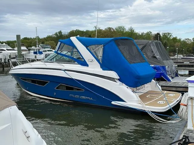 Slide: The Image of 2015 Regal 32 Express boat with blue canopy docked at marina. - 5