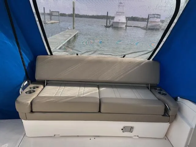 Slide: The Image of 2015 Regal 32 Express boat interior with cushioned seating and cup holders, docked by the water. - 9