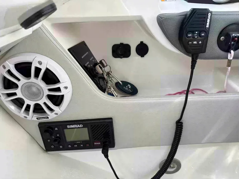 Slide: The Image of 2021 Sea Ray SLX 310 OB dashboard with speaker, Simrad radio, and key storage. - 14