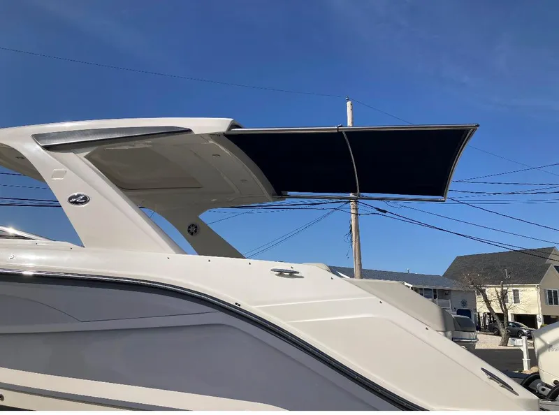 Slide: The Image of 2021 Sea Ray SLX 310 OB boat with extended sunshade under clear blue sky. - 30