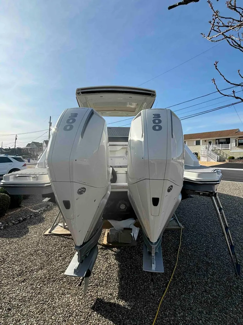 Slide: The Image of 2021 Sea Ray SLX 310 OB with dual outboard engines, parked on gravel. - 40
