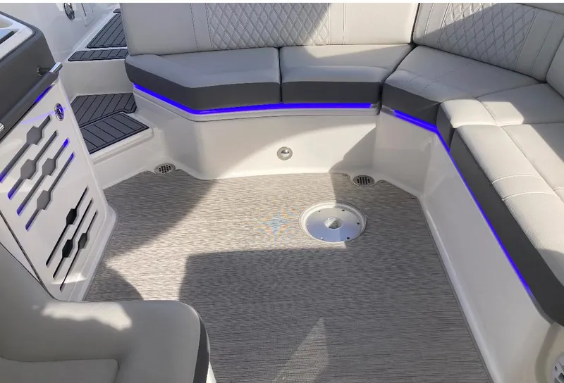 Slide: The Image of 2021 Sea Ray SLX 310 OB boat interior with cushioned seating and ambient lighting. - 9