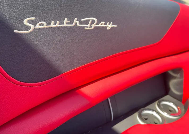 Slide: The Image of Red and black interior of 2023 South Bay 25 Sport RS9 DC with logo and cup holders. - 12