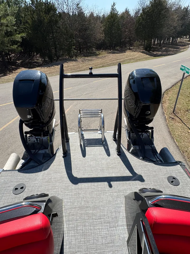 Slide: The Image of 2023 South Bay 25 Sport RS9 DC boat with dual engines and red seating, parked on a road. - 20