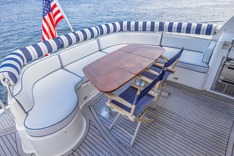 Slide: The Image of Luxurious Neptunus 54 Express yacht deck with striped seating, wooden table, and American flag. - 18
