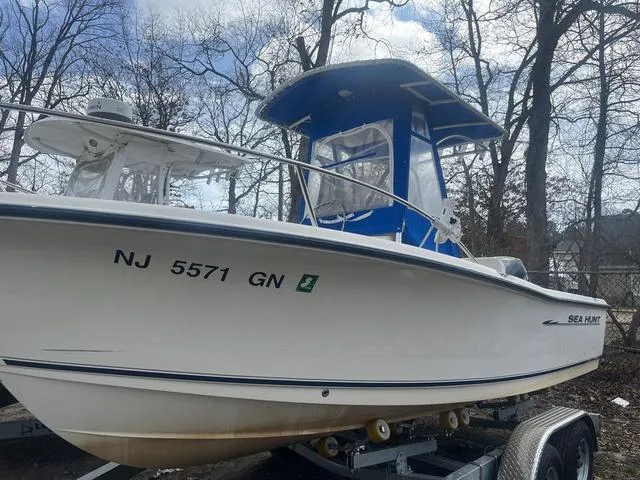 Slide: The Image of 2002 Sea Hunt 202 TRITON boat on trailer, parked outdoors, with blue canopy. - 1