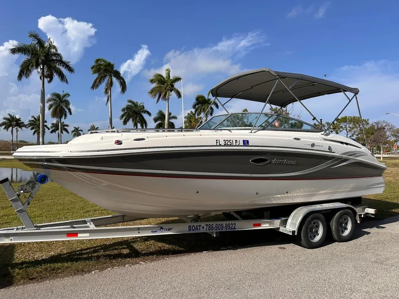 Slide: The Image of 2012 Hurricane SD2400 OB boat on trailer, parked near palm trees under a clear sky. - 7