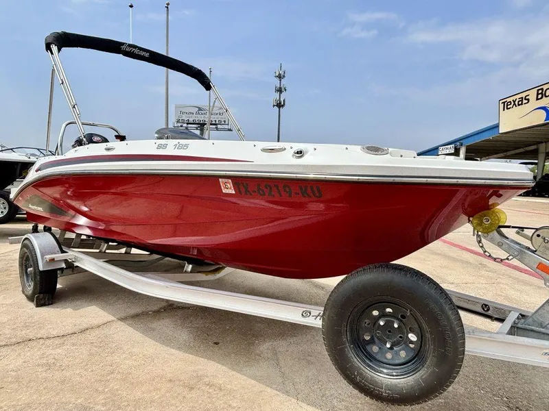 Slide: The Image of 2022 Hurricane SunDeck Sport 185 OB boat on trailer, red hull, parked outdoors. - 2